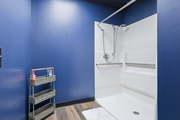Private shower room at BodyByFlo with grab bars, bench and toiletry cart