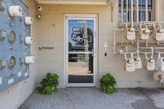 BodyByFlo glass entrance door with logo, phone number and opening hours