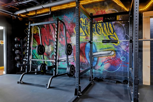 Two power racks loaded with plates in front of a large graffiti mural