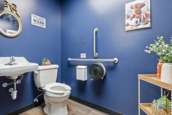 Clean accessible restroom at BodyByFlo with grab bars and hand-washing sign