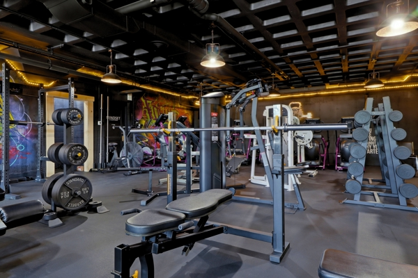 Adjustable bench and barbell station on the BodyByFlo strength floor under warm industrial lighting
