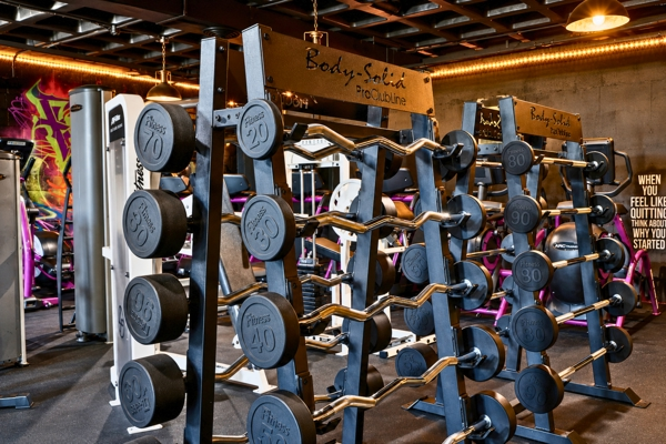 Fixed-weight barbell and curl bar racks on the BodyByFlo strength floor