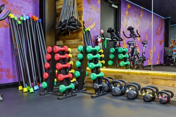 Racks of colorful dumbbells, kettlebells, weighted bars and spin bikes in the studio