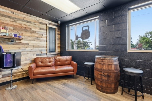Member lounge with leather sofa, reclaimed wood wall and barrel table