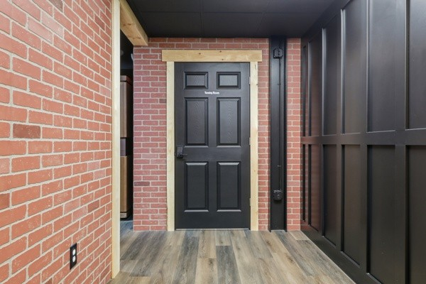 Training room door framed by exposed brick and black panelled walls