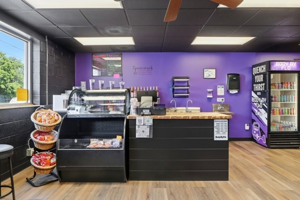 BodyByFlo smoothie bar with purple accent wall, counter and stocked drink cooler