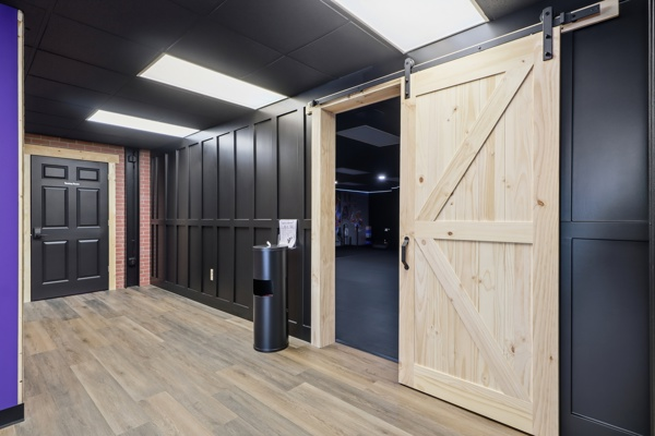Corridor with black panelled walls and a barn door leading into the studio