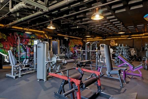 BodyByFlo main weight floor with selectorized machines, benches and graffiti murals