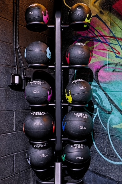 Wall-ball and medicine ball rack from 2 to 20 pounds beside a painted brick wall