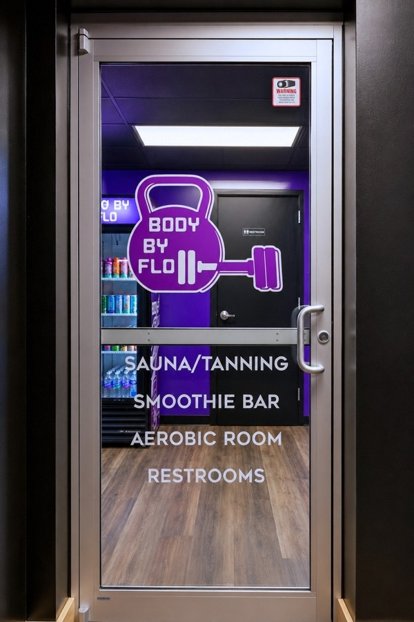Glass door listing sauna and tanning, smoothie bar, aerobic room and restrooms
